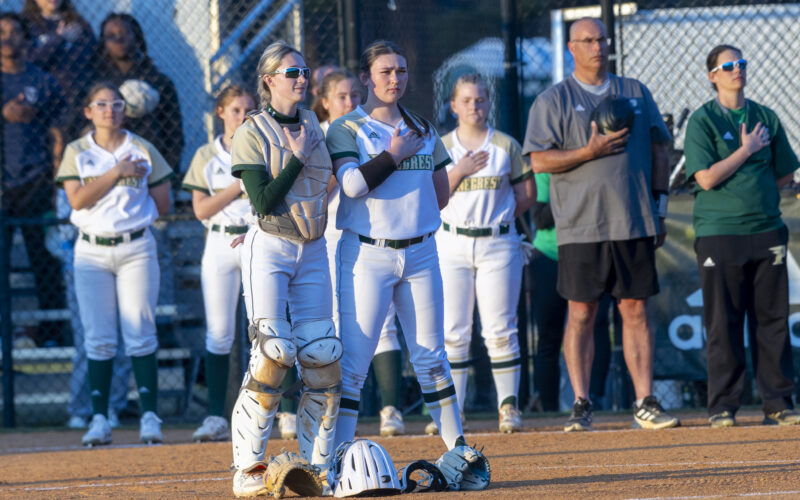 Pinecrest softball players Maggie Drake (left) and Addisyn Stayskal stand during the National Anthem before a game against Hoke County on March 20. The Patriots lost at home 15-3, though it did snap Pinecrest’s four-game scoreless streak. David Sinclair for North State Journal