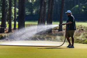 A course groundskeeper waters the grass during a break in play on Thursday.(Stan Gilliland)