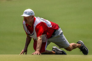 A caddie gets low to try to get a better read of the greens hills and valleys. (Stan Gilliland)