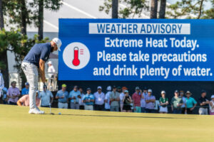 Tyrrell Hatton putts at Pinehurst No. 2 during the U.S. Open on Saturday, while a sign behind him warns the crowd to prepare for the oppressive heat. (Stan Gilliland)